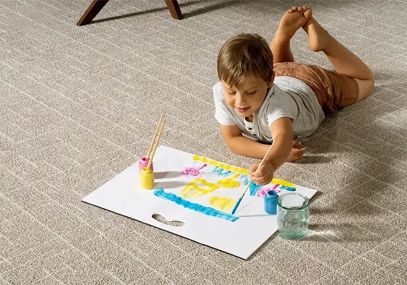 Kid draws laying on soft carpet